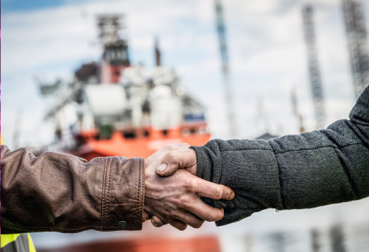 Two Men Shaking Hands With A Trawler In The Background